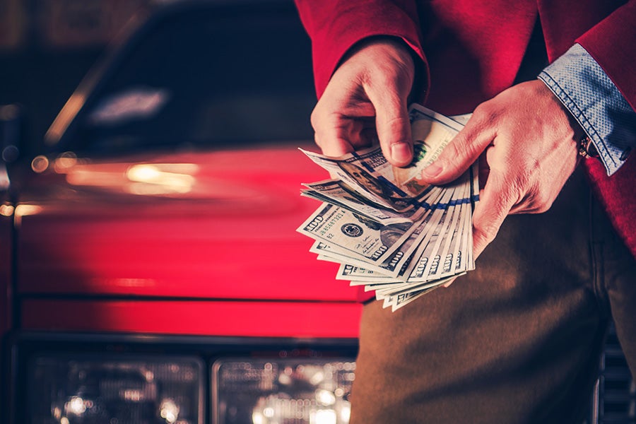 Person holding cash while evaluating vehicle trade-in options.